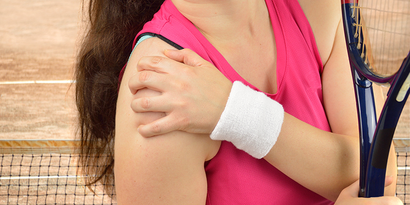 Female pickleball player holds shoulder due to injury.