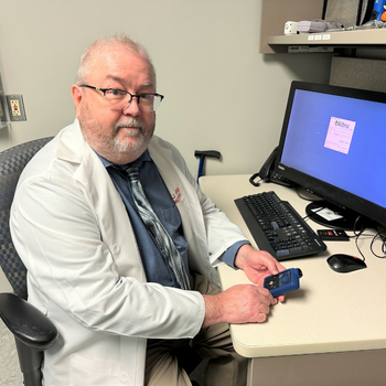 Dr. Johnson holding a diabetes technology device in a patient room.