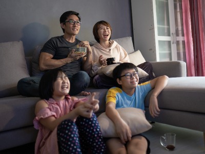 A family of four sitting in a living room watching a movie.