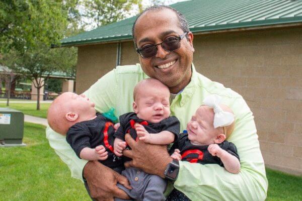 man holding three babies