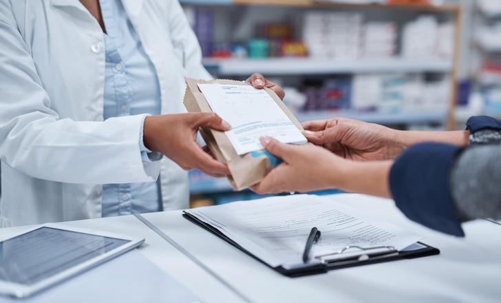 A pharmacist handing a patient medication.