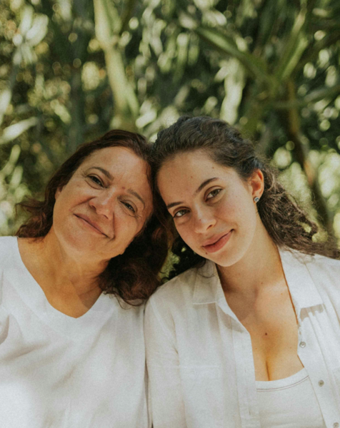 A mother and daughter smiling outdoors.