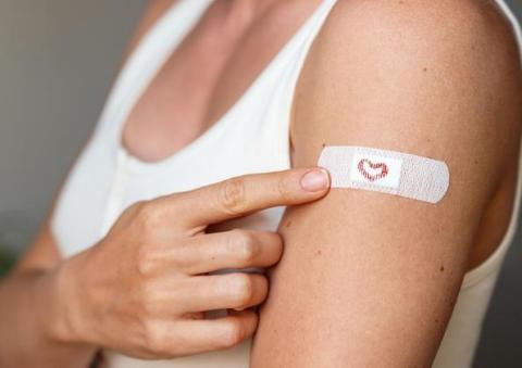 A person showing off their band aid after a shot.