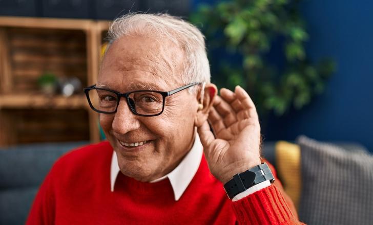 Man holding hand by his ear to listen with hearing aid
