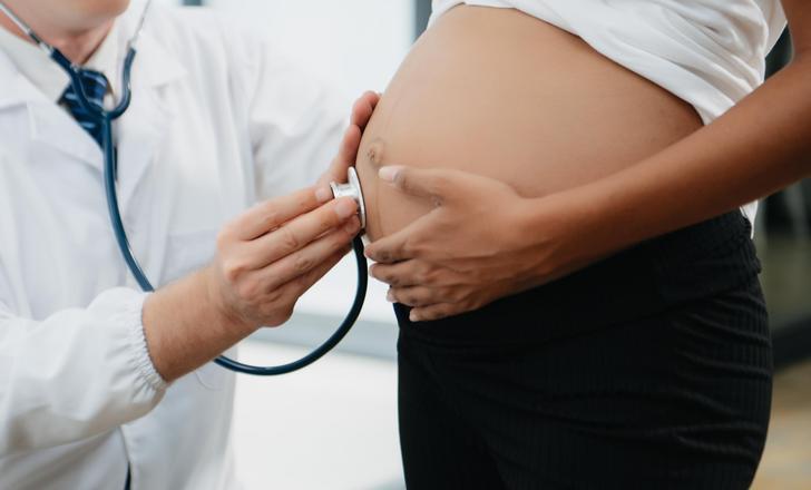 A doctor listening to a pregnant woman's belly.
