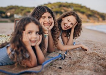 3 girls tanning on a beach.