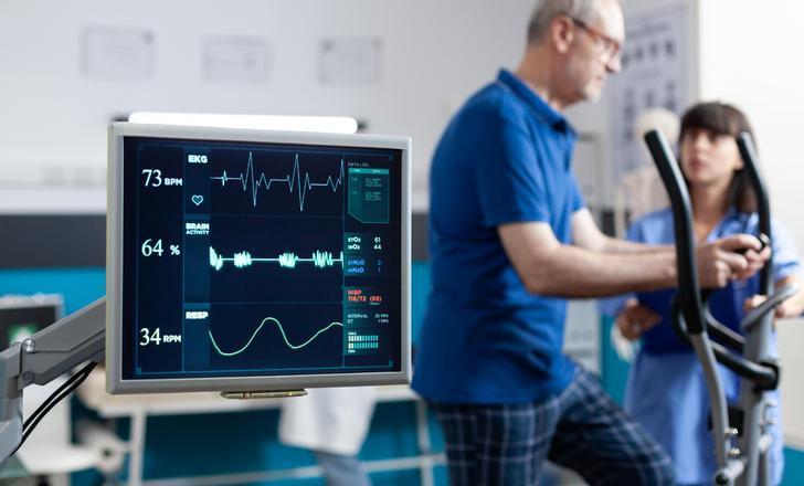 A provider helping a patient in the cardiac rehab gym.
