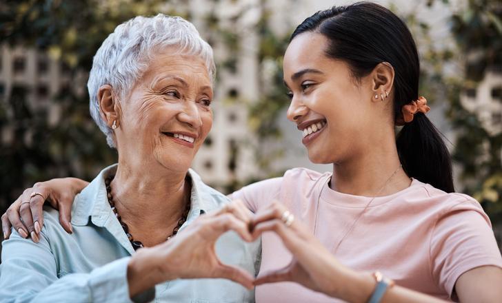 Mom and daughter holding up hands in heart shape