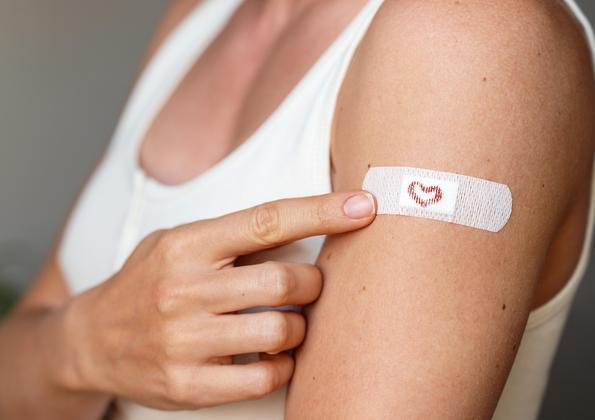 A person showing off their band aid after a shot.