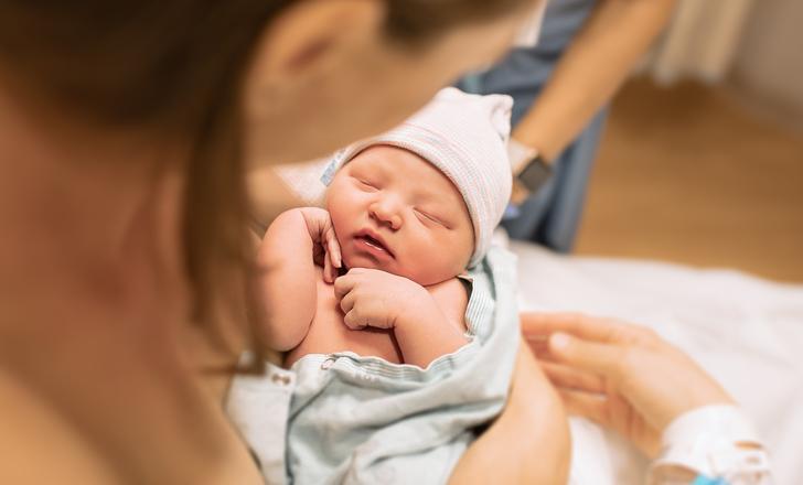 A mother and a newborn baby in a hospital room.