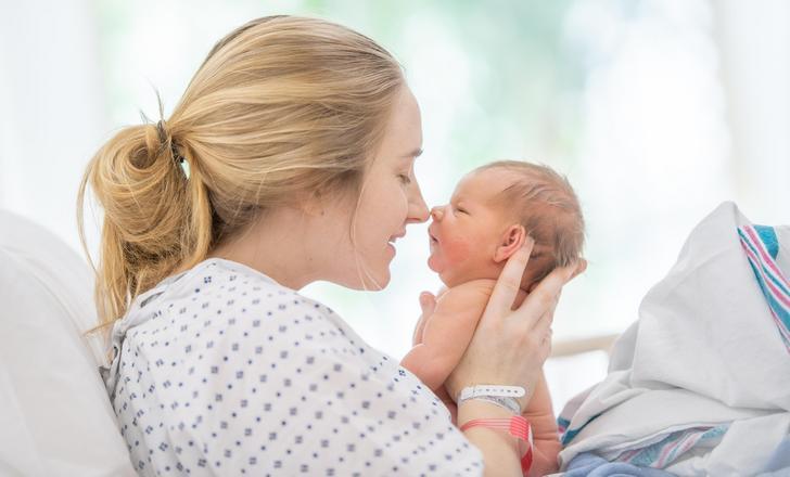A mother holding her newborn baby in a hospital bed.