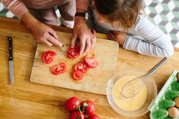 Mother teaching her daughter how to cut vegetables