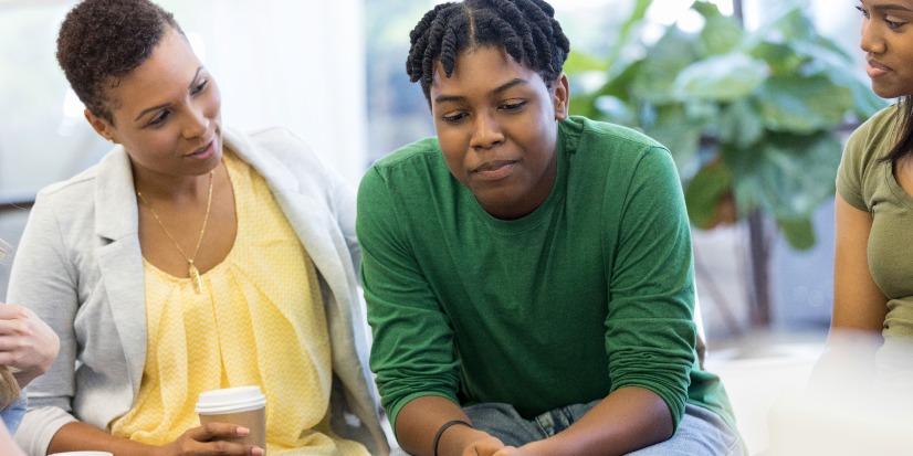 A parent and a teenager sitting in a circle with a group.
