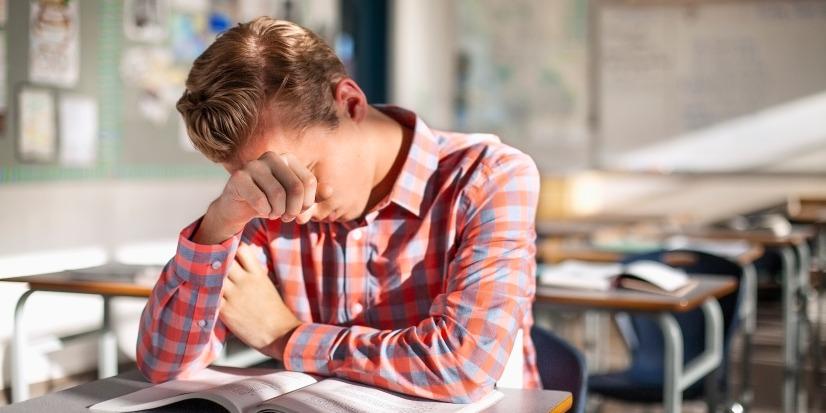 A student sitting at a desk looking stressed.