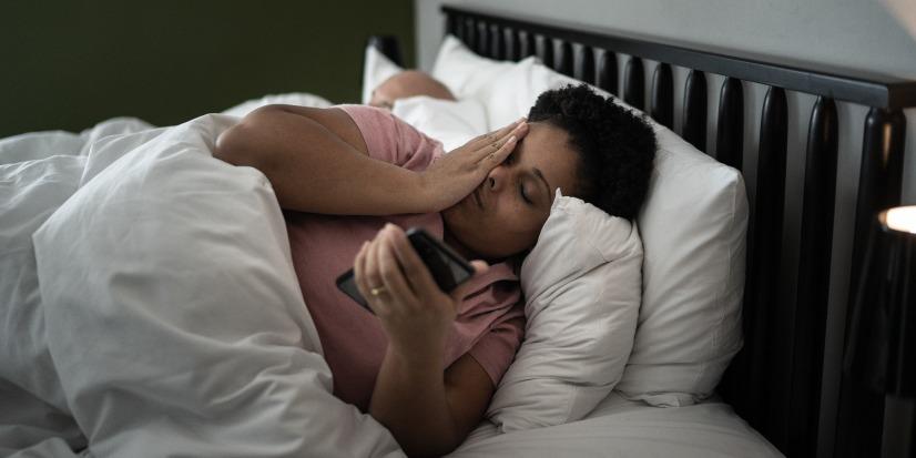 A woman on her phone in a bed.
